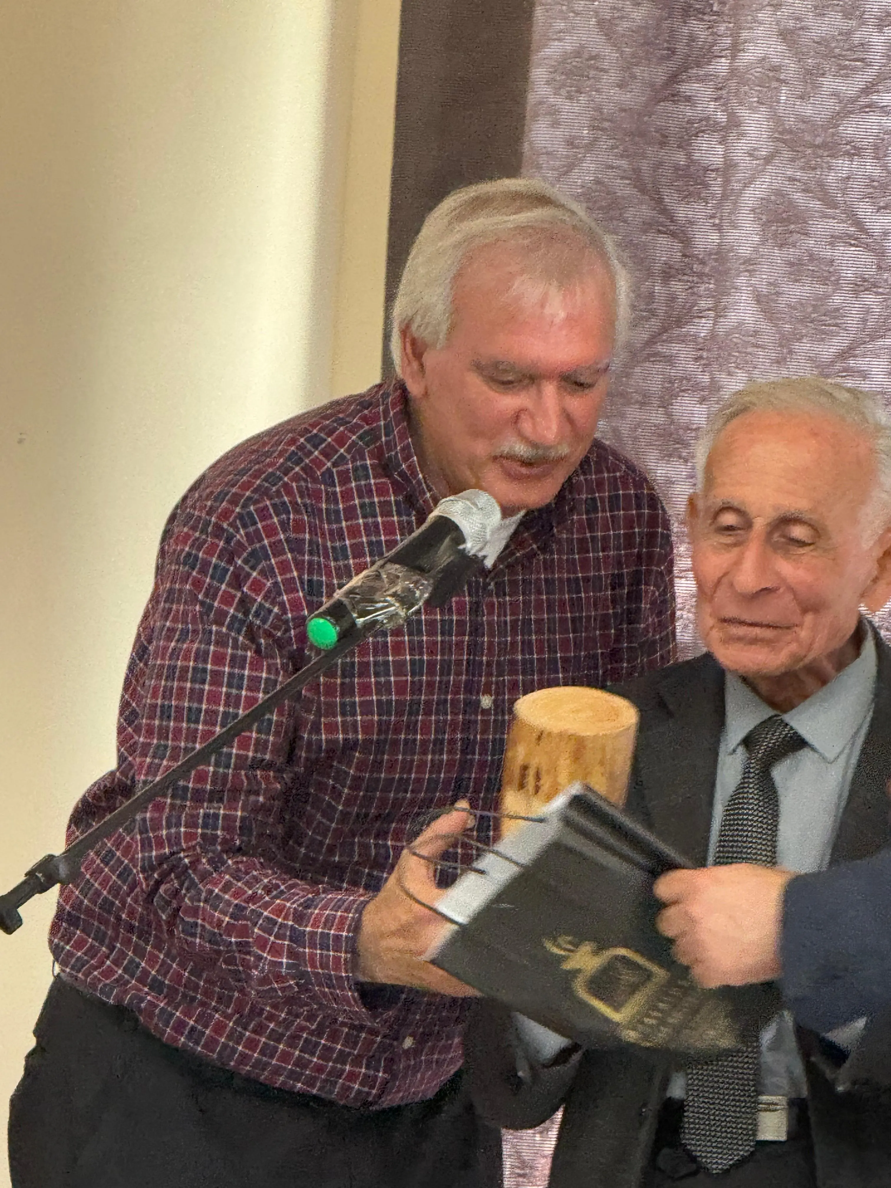 Two church leaders holding an open Bible and a wooden gift during a service of appreciation