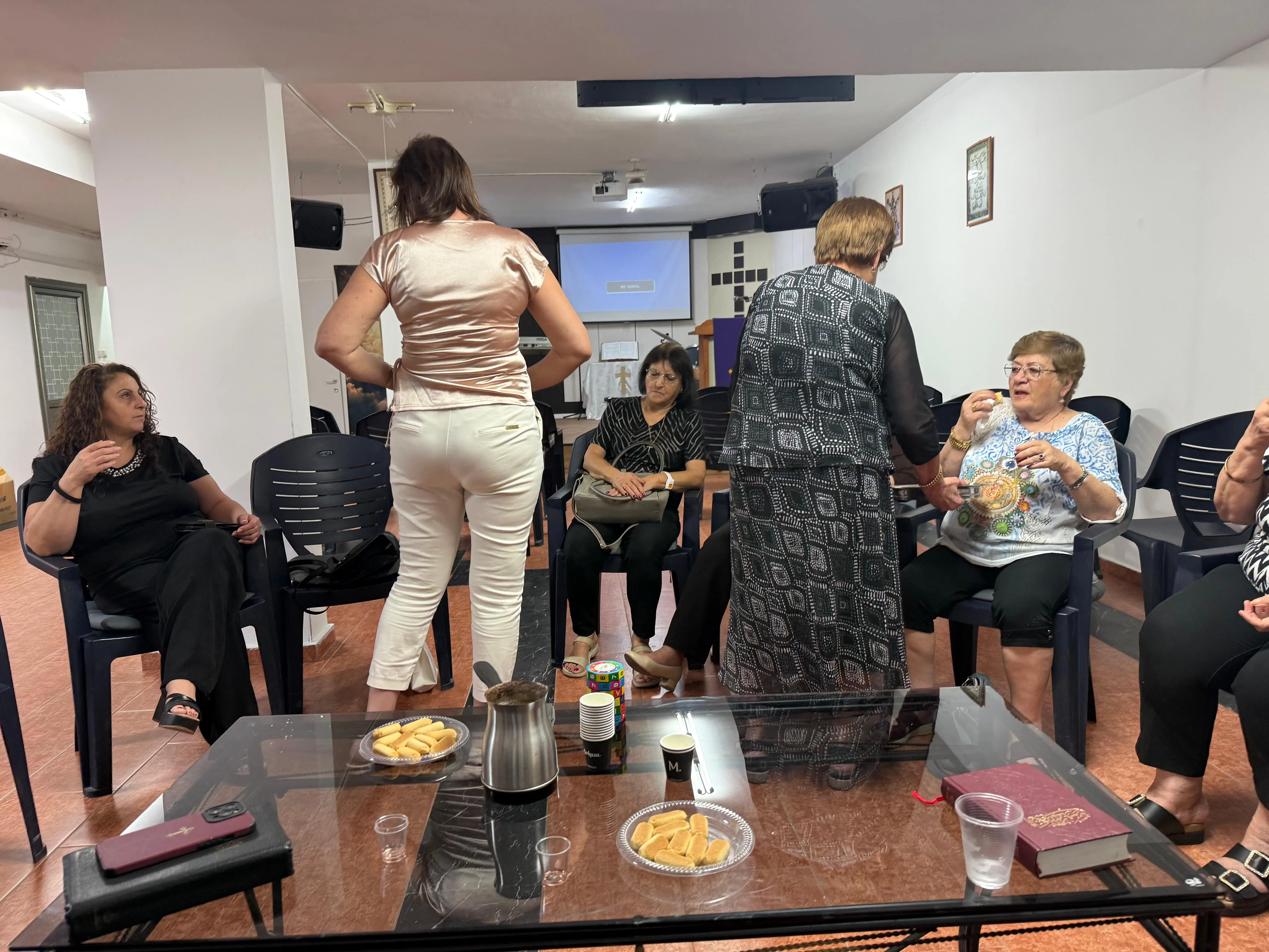 Church members sharing tea, coffee and biscuits around a glass table after the service