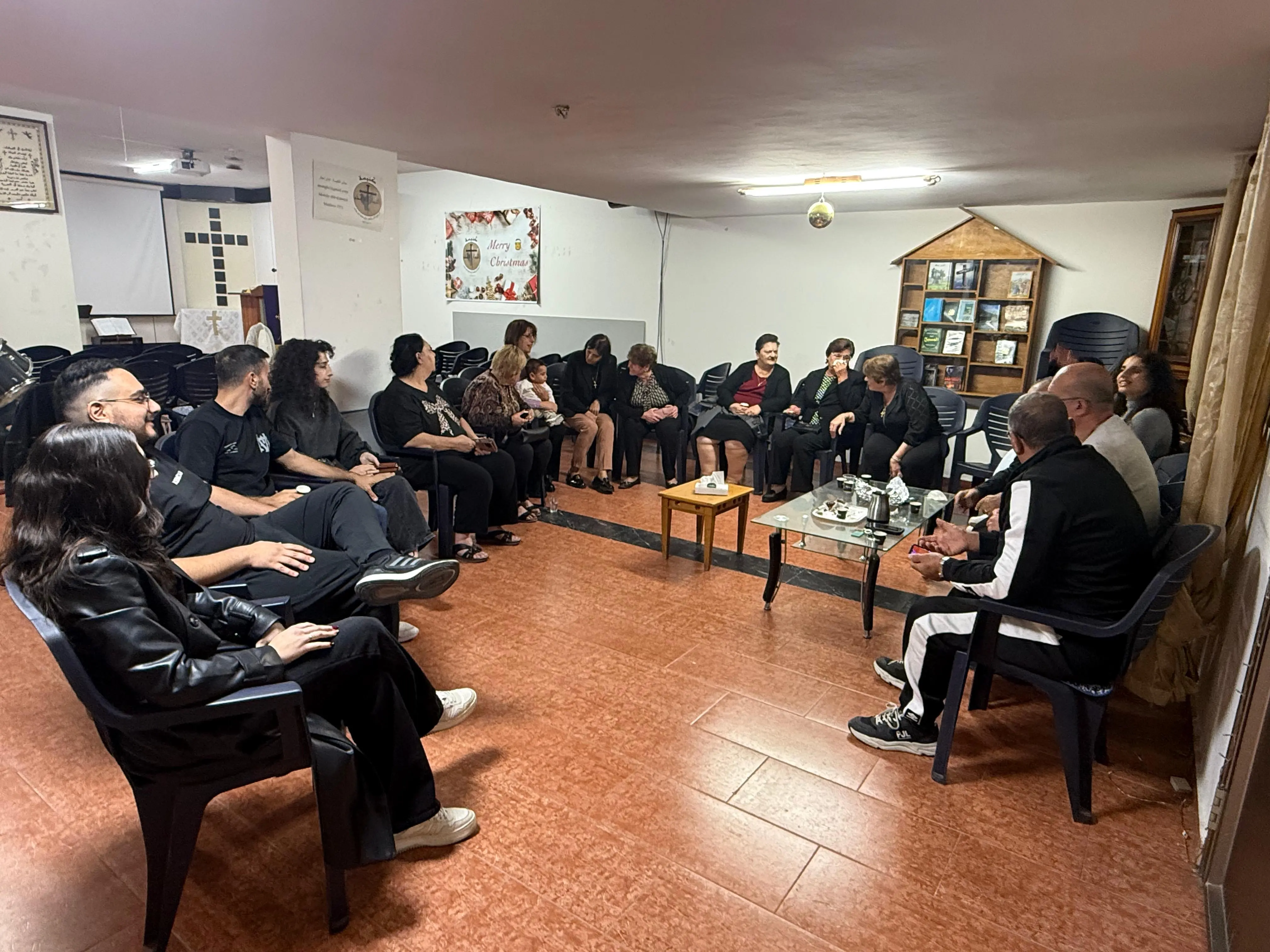 The church community gathered in a circle for fellowship, with tea on the table between them