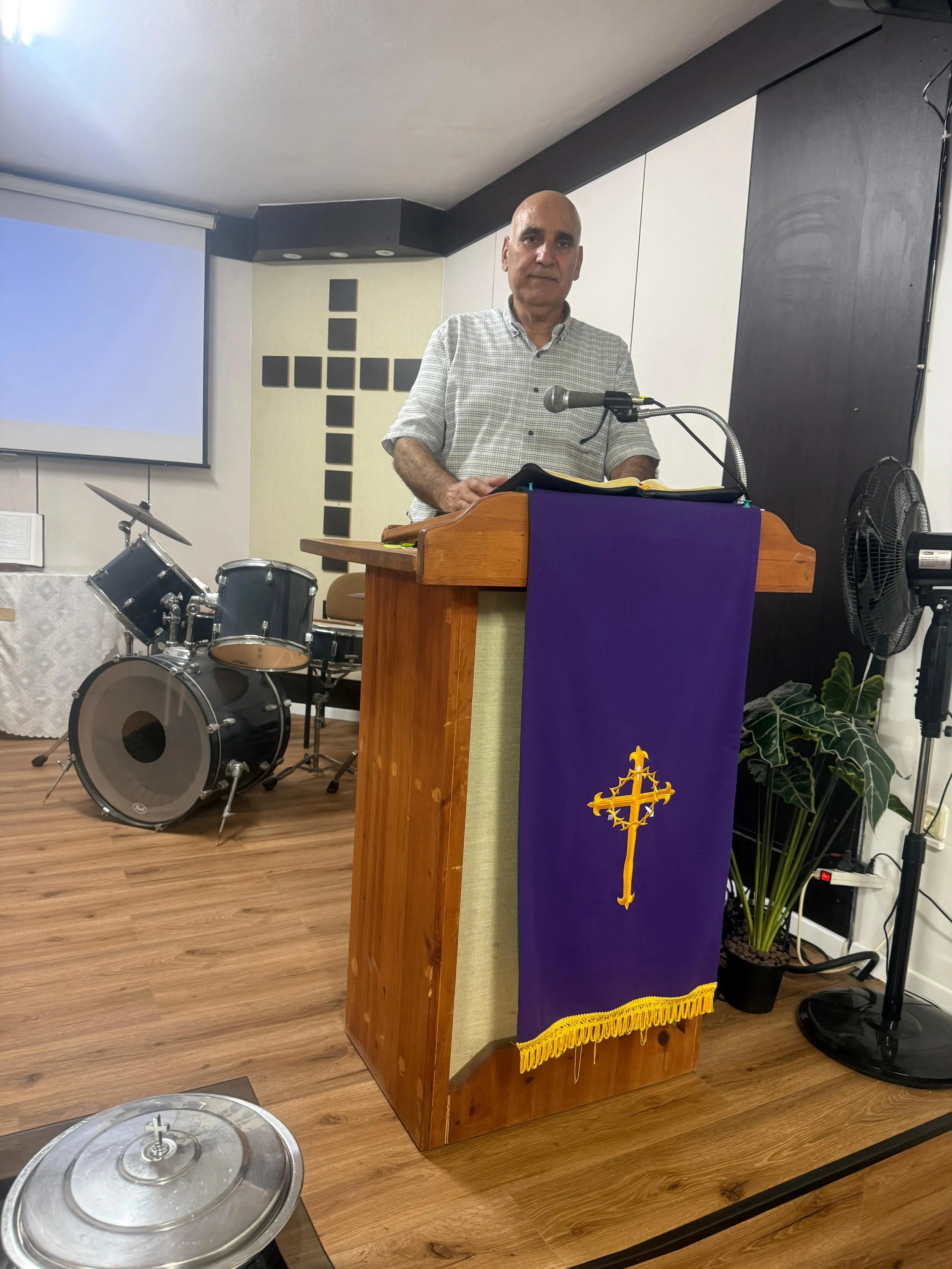 A pastor reading the Bible at the pulpit in front of a wall covered with crosses