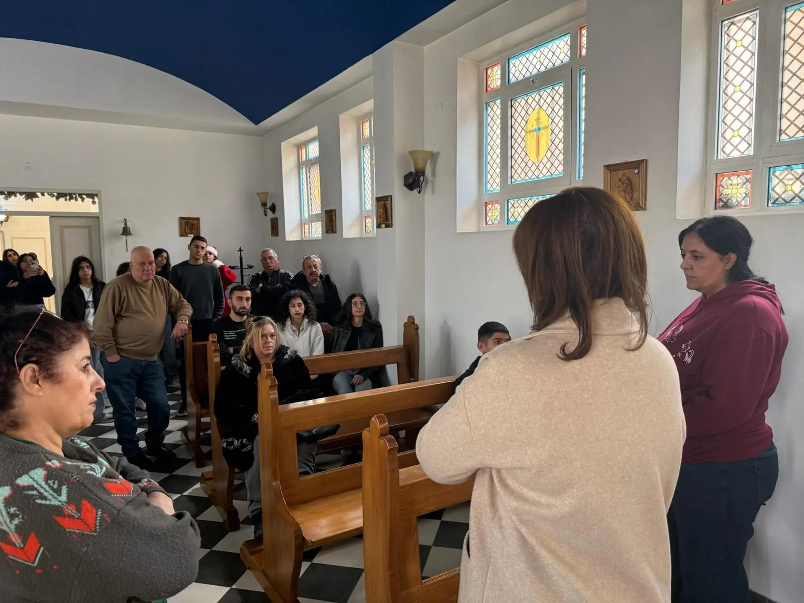 The congregation gathered in an ancient church with stained-glass windows and a blue vaulted ceiling