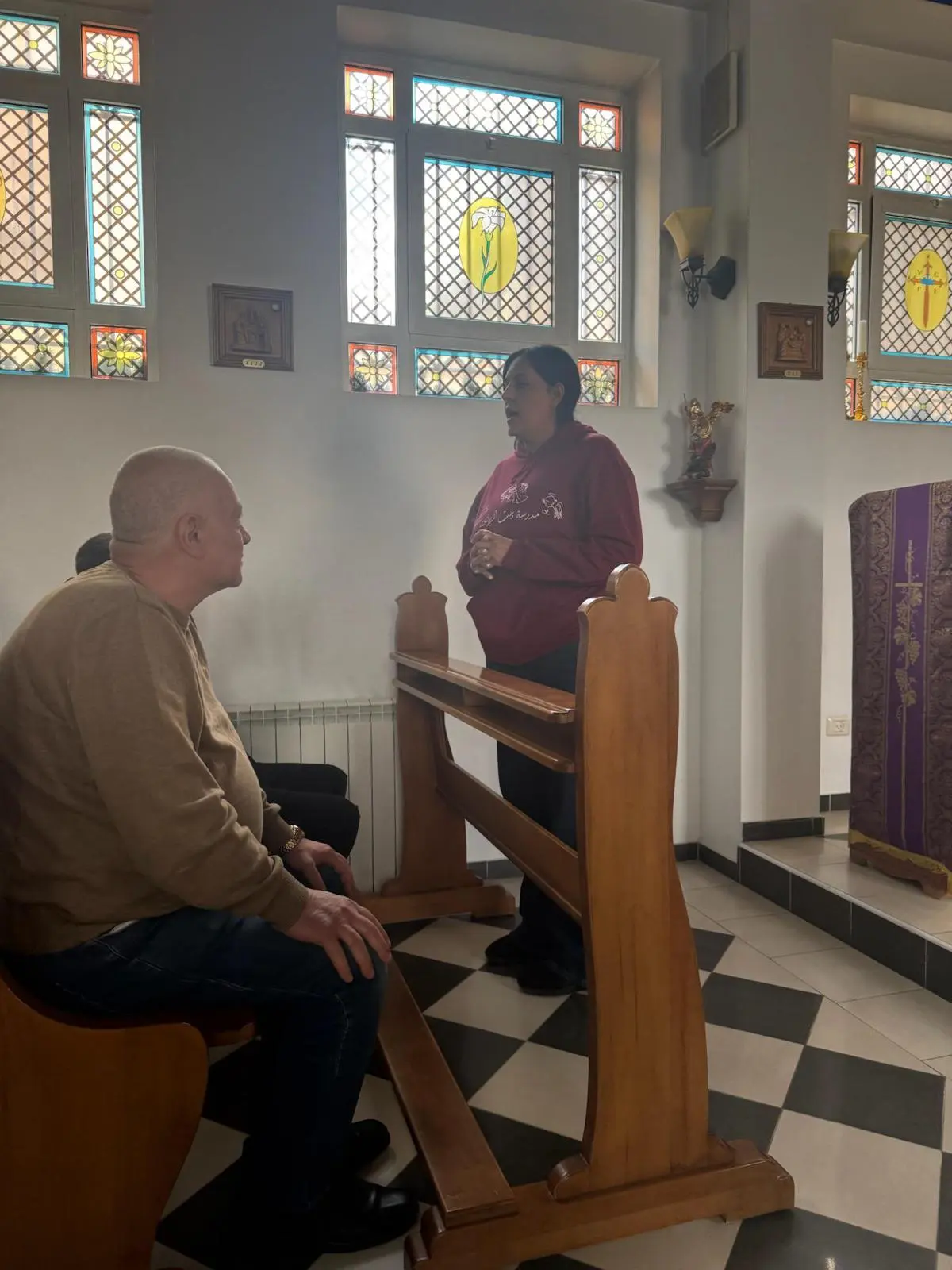 Stained-glass windows and a wooden prayer desk in a historic church in the Holy Land