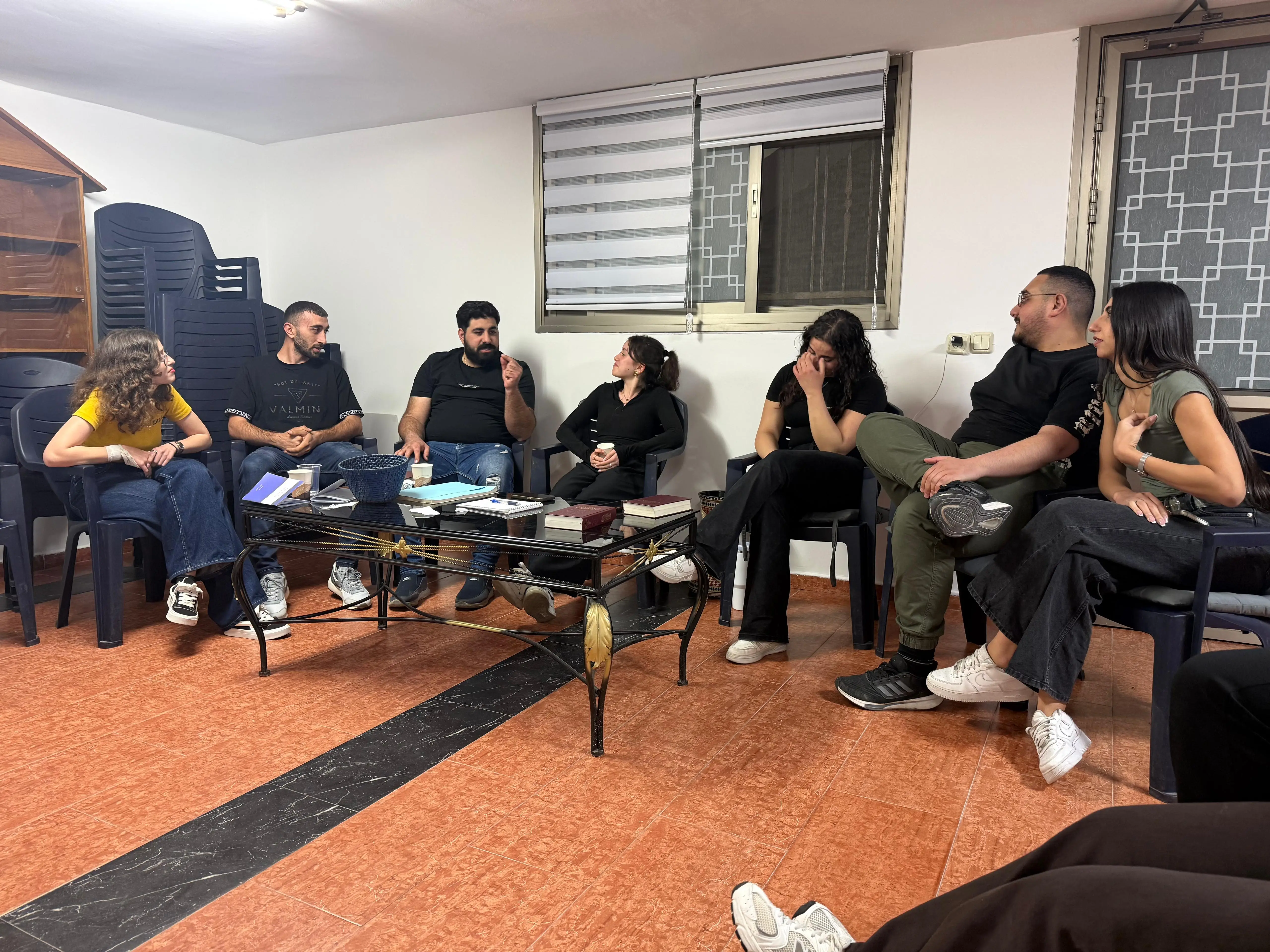 Young adults of the church sitting in a circle with open Bibles during a discipleship meeting